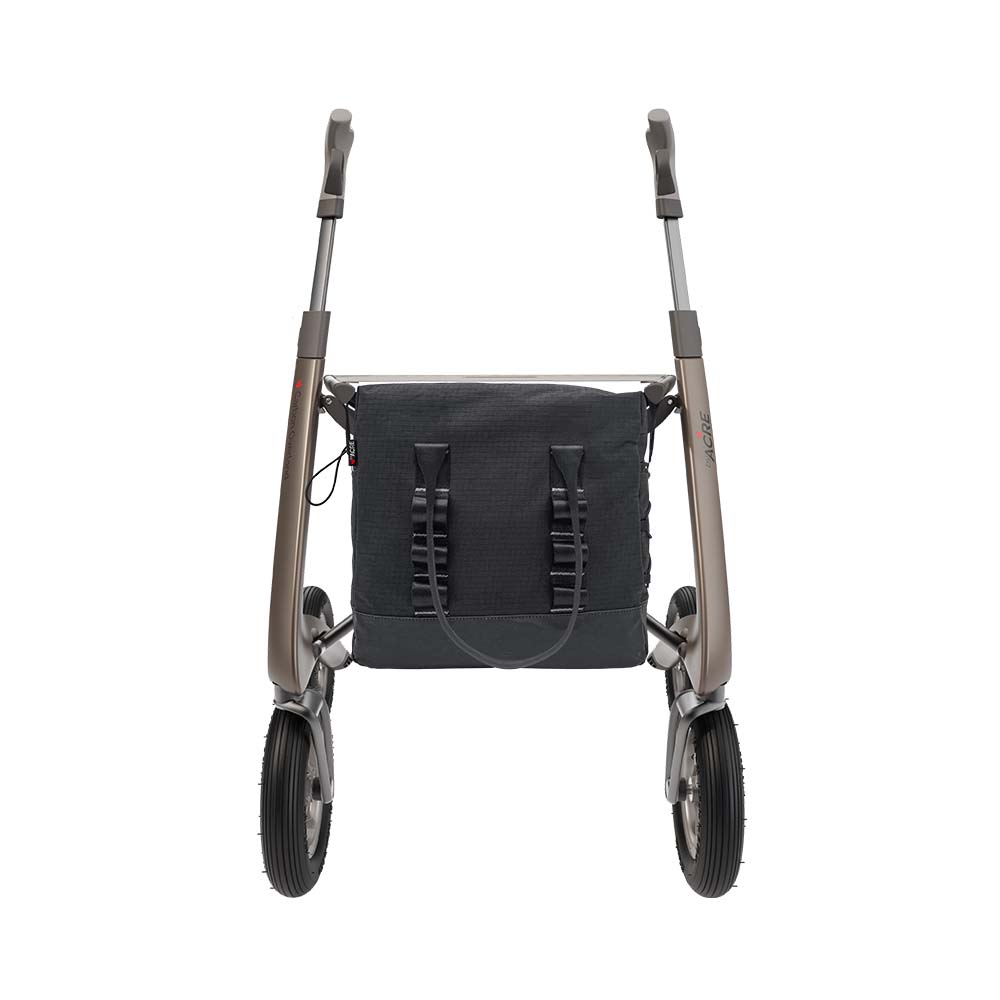A rollator walker with a black mesh storage bag attached to the front frame, shown from the rear against a solid white background.