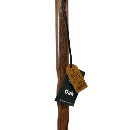 Brazos Twisted Oak Backpacker Walking Stick full length view showing natural wood grain, twisted design, and Brazos "Oak – Made in the USA" hang tag on white background