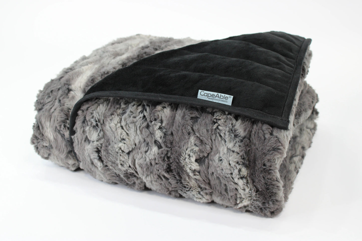 Folded CapeAble weighted blanket in tranquility gray swirl faux fur exterior with quilted black interior lining, displayed on white background