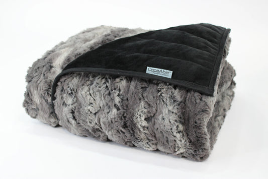 Folded CapeAble weighted blanket in tranquility gray swirl faux fur exterior with quilted black interior lining, displayed on white background