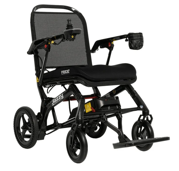 A black electric wheelchair with a mesh backrest, padded seat, three wheels, and a footrest, photographed on a clean white background. The brand name 'Jazzy' is visible on the frame.