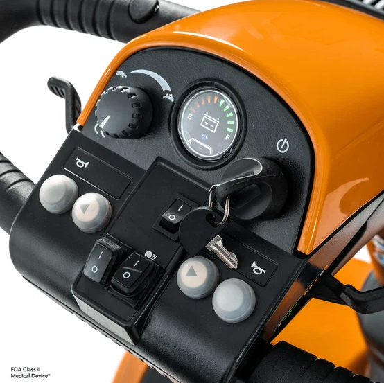 Close-up of the control panel and handlebar area of an power scooter, featuring a glossy orange and black dashboard with a round fuel gauge, power switch, and various control buttons.