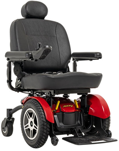 A red and black power wheelchair with a black padded seat, headrest, armrests, and large rear wheels, shown on a plain white background. The brand name 'Jazzy' is visible on the red front body panel.